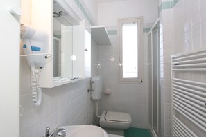 A bathroom with a white sink, a toilet, a hairdryer, and a mirror.