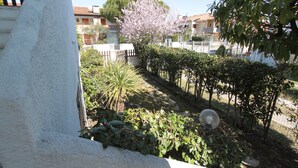 A garden with a variety of plants and a tree with pink blossoms.