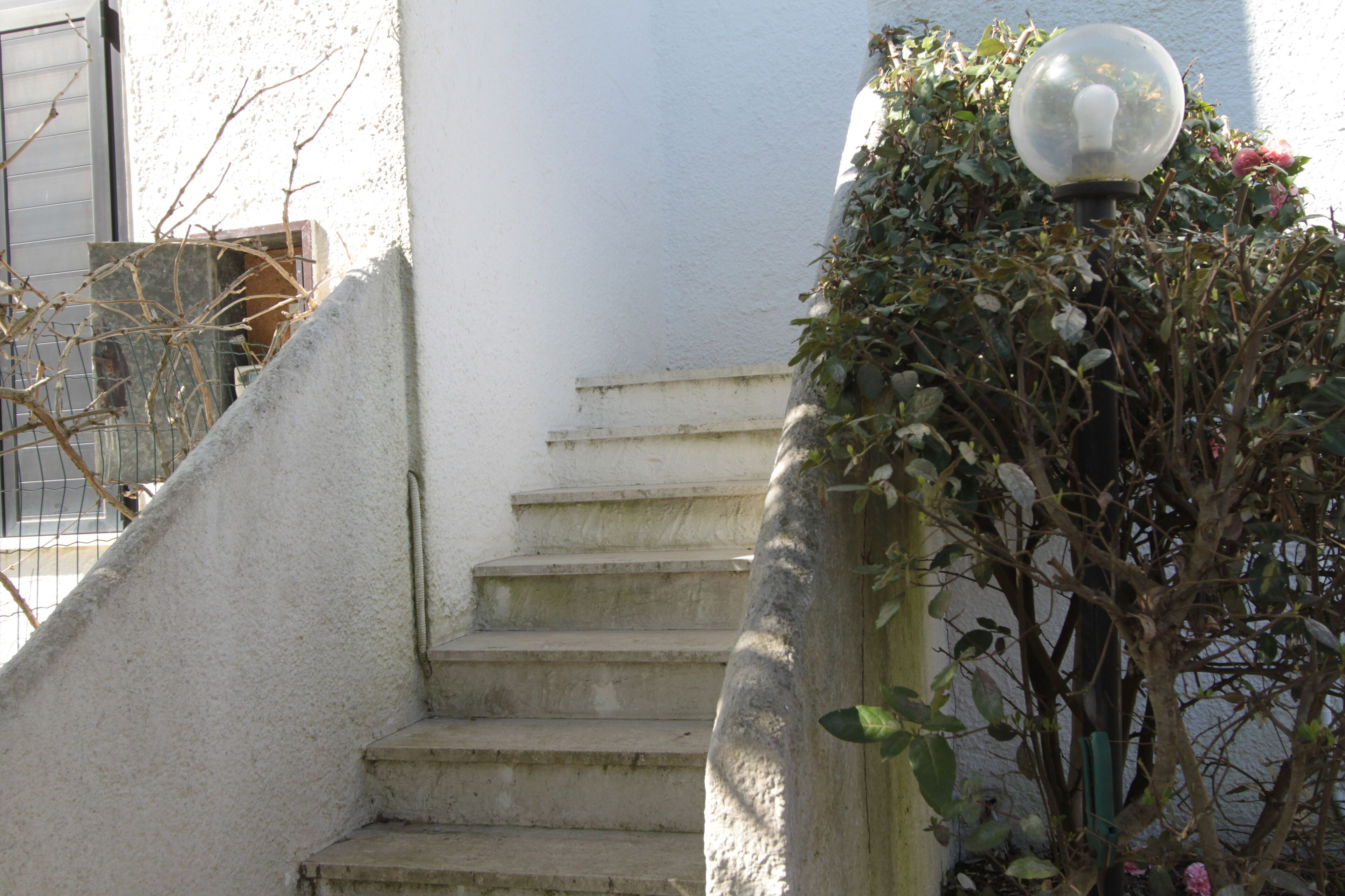 Un escalier avec un mur blanc et un lampadaire doté d’un luminaire sphérique.