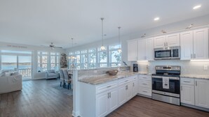 Una cocina moderna con armarios blancos, una isla grande y vistas al exterior.