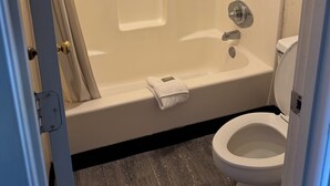 A bathroom with a bathtub, toilet, and shower curtain.