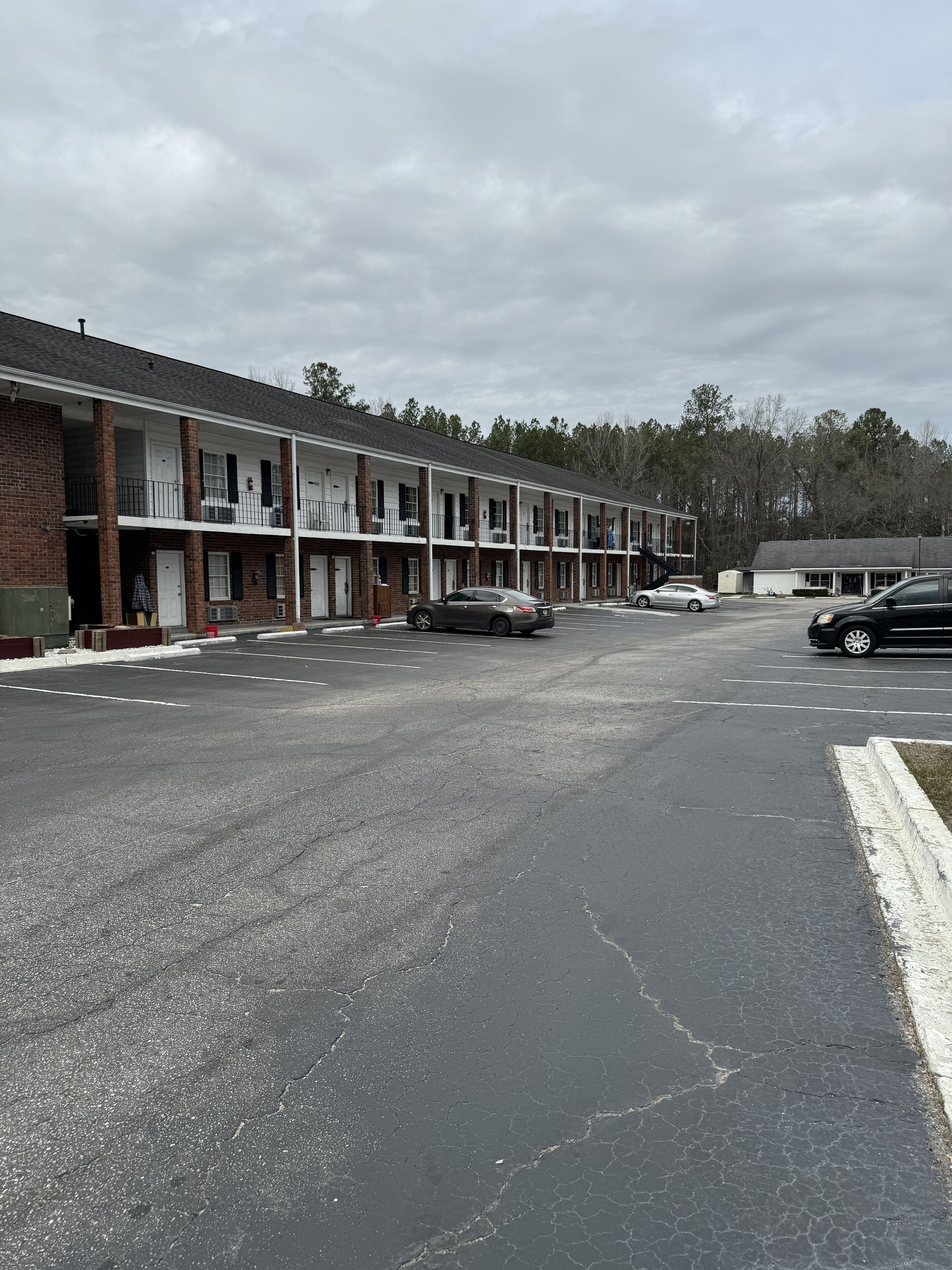 A row of motel-style buildings with a parking lot in front.