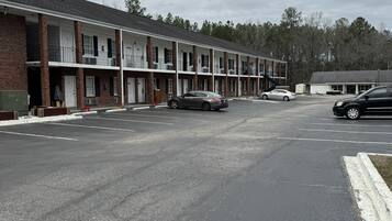 A row of motel-style buildings with a parking lot in front.