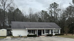 A single-story building with a porch, a garage, and a parking lot.