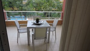 Enjoy a peaceful moment on the balcony with a table and chairs, surrounded by a serene view of trees and a nearby building.