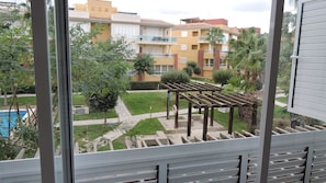Enjoy a serene view from this balcony overlooking a residential area with a pool and well-manicured lawn.