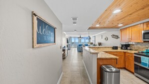 Una cocina moderna con armarios de madera, encimera de granito y un cubo de basura de acero inoxidable.