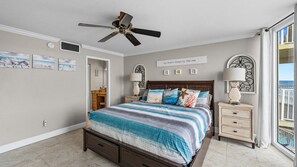 A bedroom with a bed, a ceiling fan, a nightstand, a dresser, and a window with a view. - #603 Shores Club Oceanfront Traffic Free Beach 2/2 (Daytona Beach Shores)
