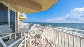 A balcony with a view of the ocean, featuring a table and chairs.