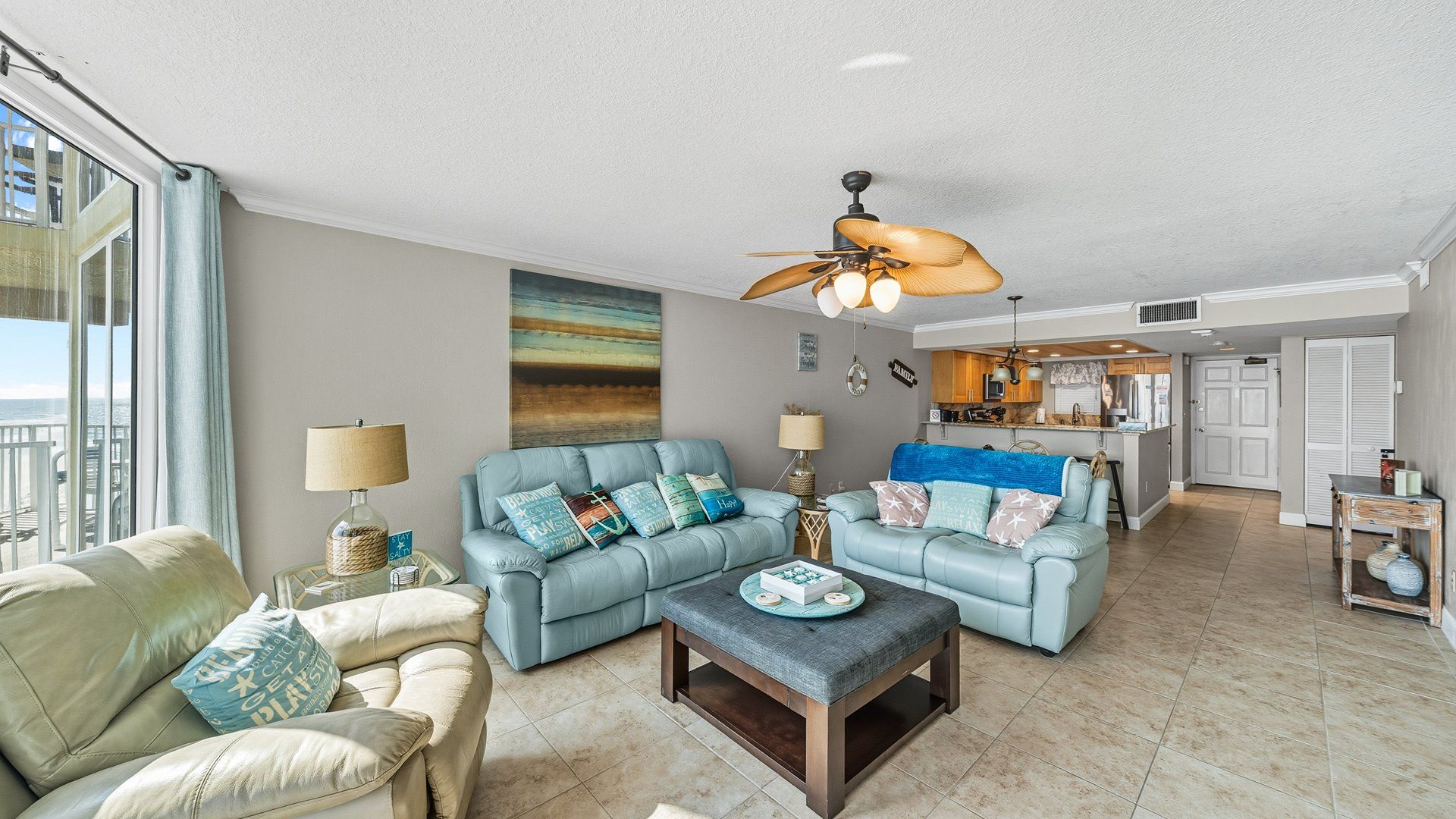 A living room with two light blue sofas, a wooden coffee table, and a ceiling fan.