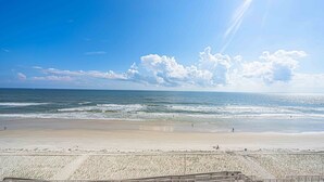 Una playa con orilla arenosa y un paseo marítimo de madera que conduce al agua.