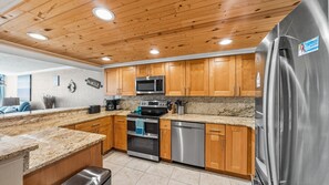 A modern kitchen with wooden cabinets, stainless steel appliances, and granite countertops.