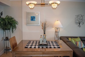A dining area with a table, chairs, a chandelier, a lamp, a framed picture, and a potted plant.