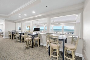 Une salle à manger spacieuse avec vue sur l’océan, comprenant une longue table et de nombreuses chaises.