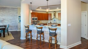 A modern kitchen with wooden cabinets, stainless steel appliances, and a central island with bar stools.