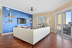 Relax in this stylish living room with a large sofa, flat-screen TV, and beautiful views of the surrounding cityscape.
