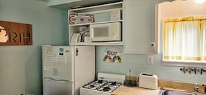 A kitchen with a refrigerator, microwave, stove, and toaster.