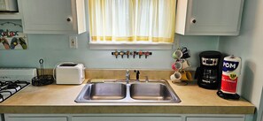 A kitchen with a double sink, a toaster, a coffee maker, and a bag of POM super towels.
