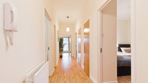 Un couloir doté d’un plancher en bois, de murs blancs et de portes donnant sur les chambres.