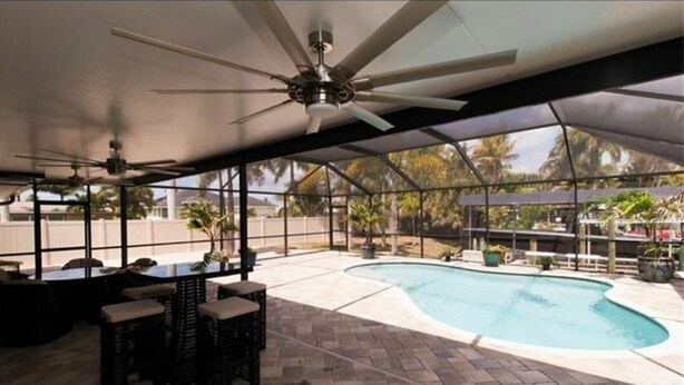 A covered outdoor area with a pool, seating, and ceiling fans. - The Boat House (Cape Coral)