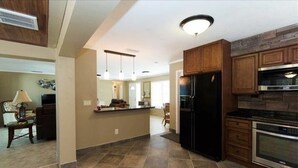 A spacious kitchen with a large island, dark cabinetry, and modern appliances. - The Boat House (Cape Coral)
