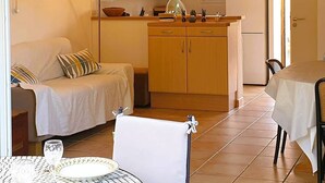 Un espacio habitable compacto con kitchenette, comedor y sofá.