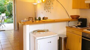 Cocina pequeña con refrigerador, cafetera y cubo de basura.