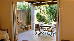 Un espacio habitable de concepto abierto con una mesa de comedor y sillas, un banco y una planta en maceta.