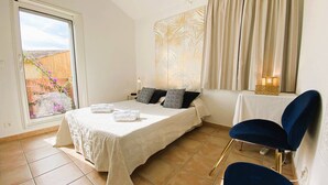 Un dormitorio con cama, una silla, una mesa y vistas al exterior.