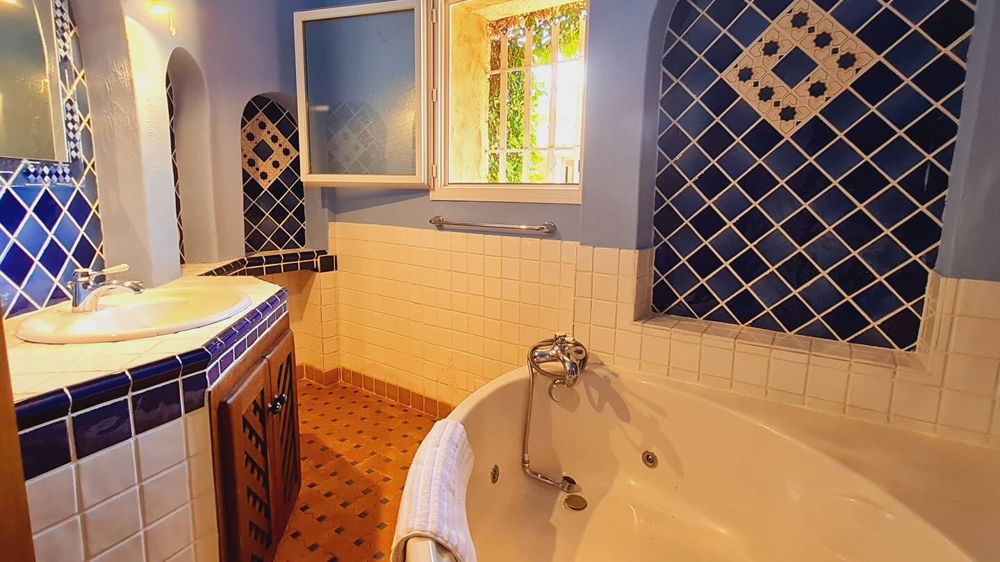 Ein Badezimmer mit einer Badewanne, einem Waschbecken und einem Fenster mit Blick auf Grünflächen.