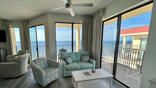 Un balcón espacioso con vista al océano, amoblado con sofá, sillón y una mesita de centro.