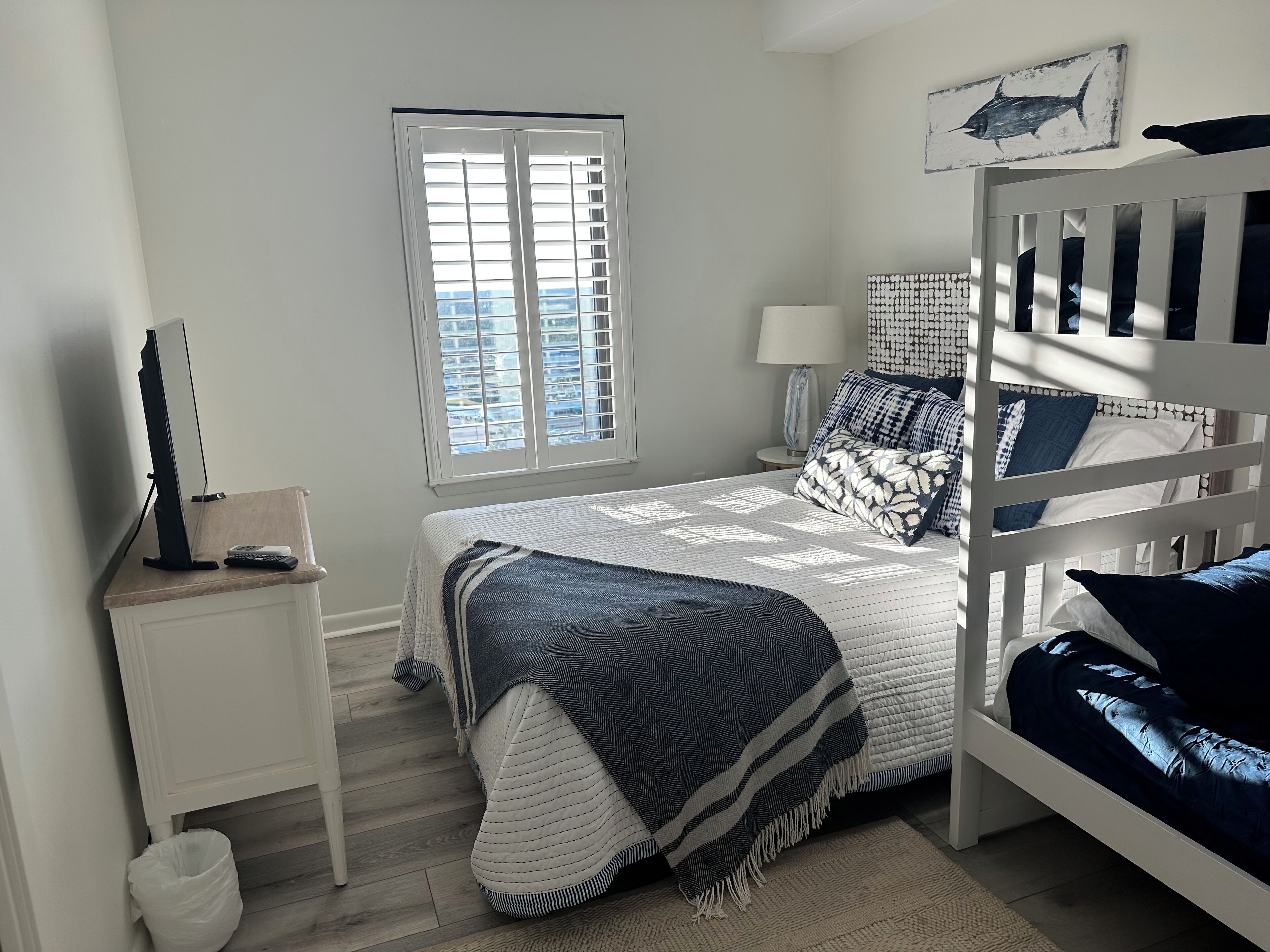 Un dormitorio con cama, mesita de noche, escritorio, ventana y literas.