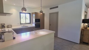 A modern kitchen with a central island, built-in appliances, and pendant lighting. - Villa Tinuta. 8 pers, piscine chauffée, 5 min plage en voiture (SAINTE LUCIE DE PORTO VECCHIO)