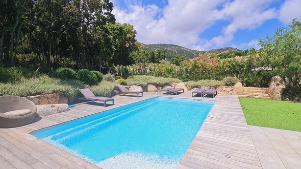 A rectangular swimming pool with a wooden deck, surrounded by greenery and a stone wall. - Villa Tinuta. 8 pers, piscine chauffée, 5 min plage en voiture (SAINTE LUCIE DE PORTO VECCHIO)
