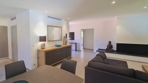 A modern living room with a dining area, a kitchen, and a TV. - Villa Tinuta. 8 pers, piscine chauffée, 5 min plage en voiture (SAINTE LUCIE DE PORTO VECCHIO)