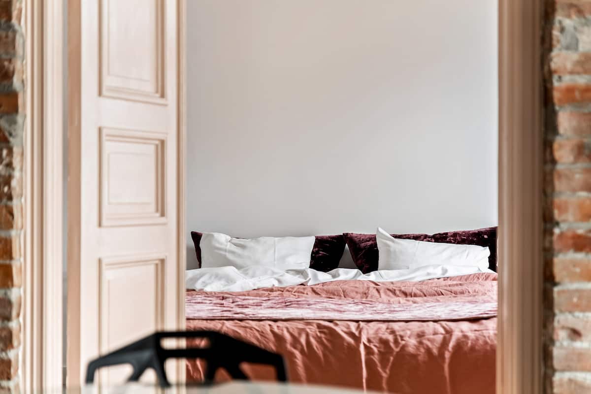 Un dormitorio con cama, almohadas y una pared de ladrillo.