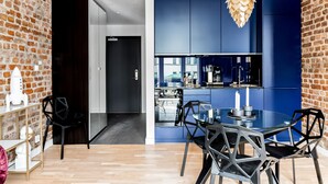 A modern kitchen with blue cabinets, a glass dining table, and black chairs.