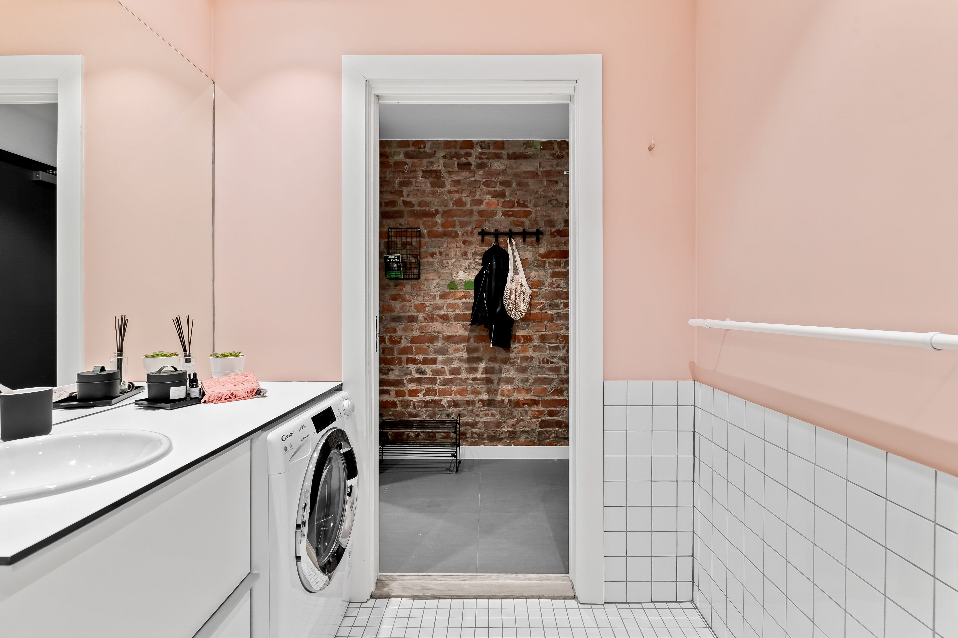 Un bagno moderno con lavandino bianco, lavatrice e parete in mattoni.