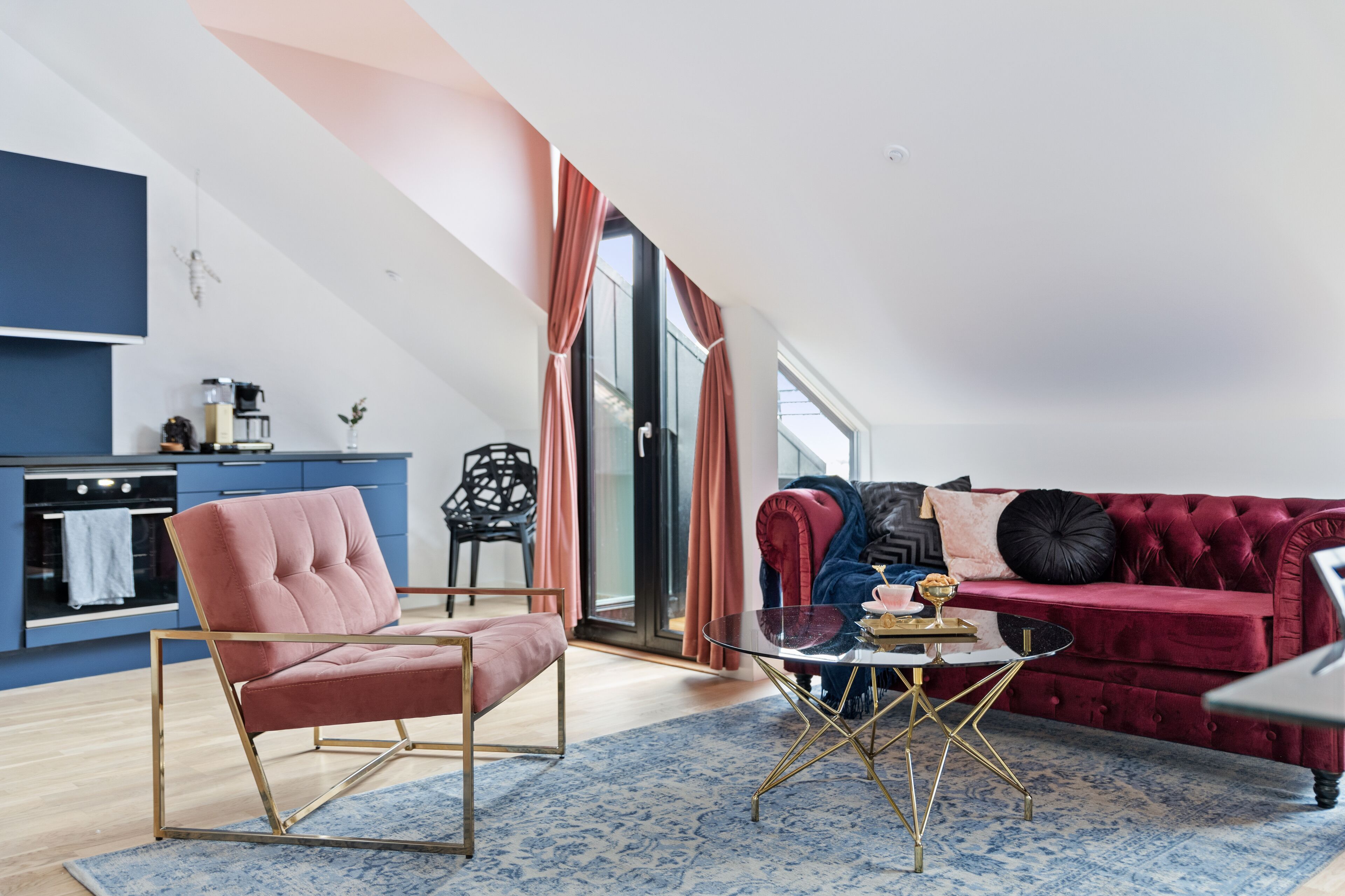 A modern living room with a red sofa, a pink chair, and a glass coffee table.