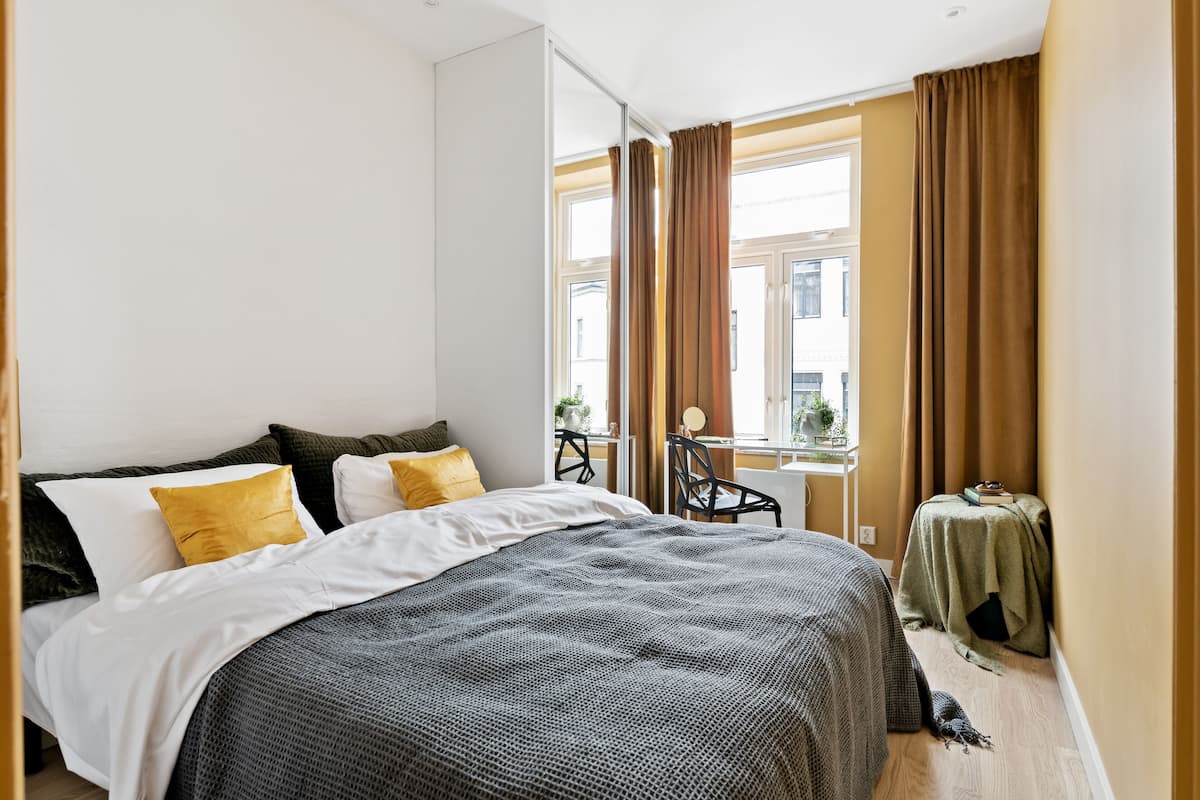 Una habitación de hotel con una cama, una mesita con una silla y una ventana con cortinas.