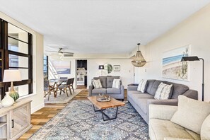 A spacious living room with a sofa, a coffee table, and a dining area with chairs.