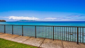 A coastal view with a clear blue sky, turquoise sea, and a distant mountain range. - Hale Ono Loa 106 - Relax Steps Away from the Ocean (Lahaina)