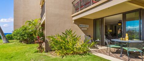 A hotel with a 'Beach House' sign, outdoor seating, and a well-maintained lawn.