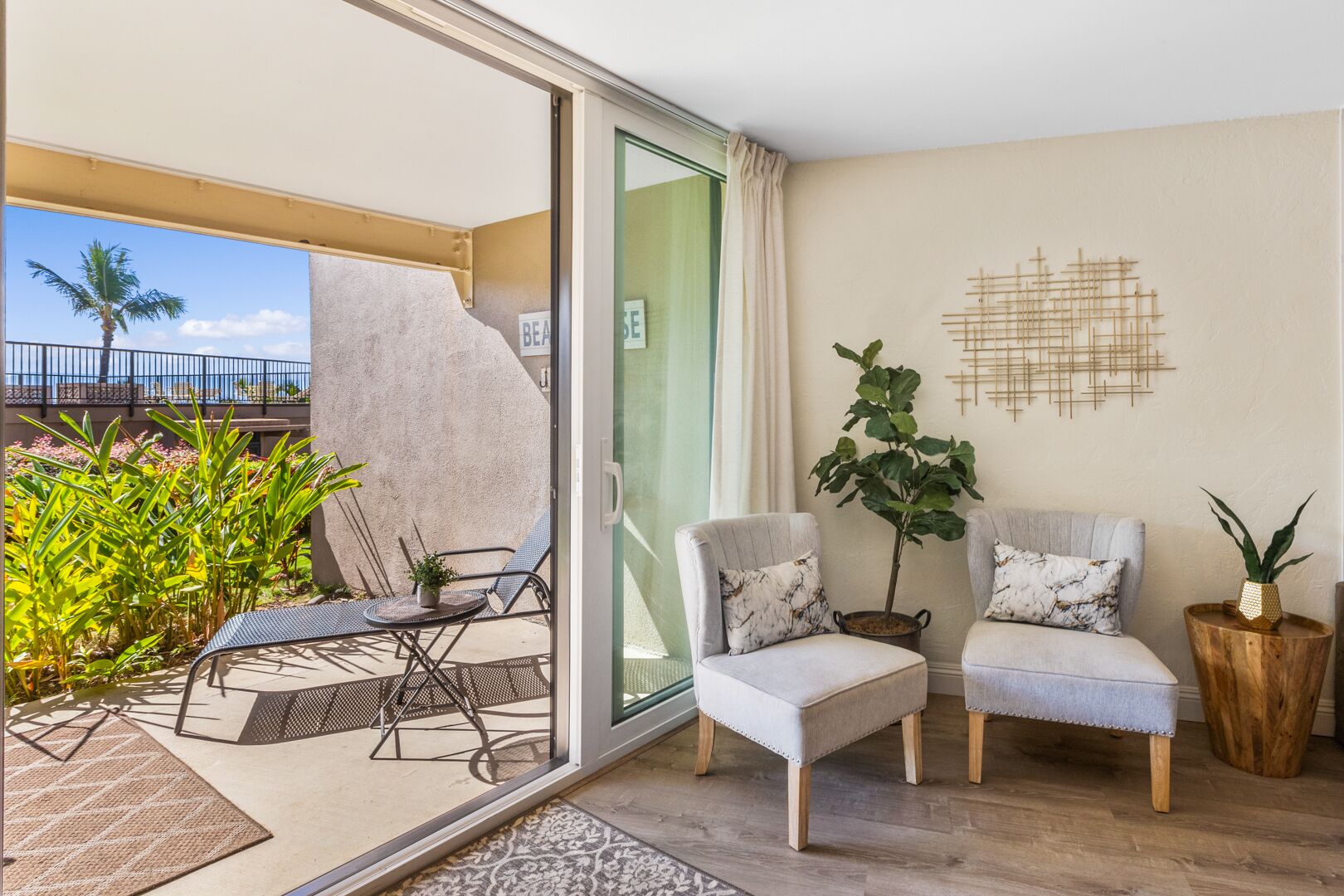 Ein Balkon mit Glastür, zwei Stühlen, einem kleinen Tisch und einem Blumentopf.
