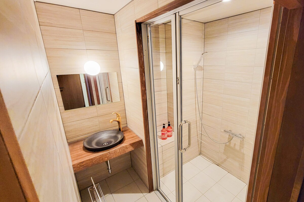 Un bany modern amb un lavabo, mirall i dutxera amb envàs de vidre.