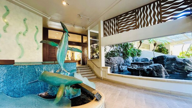 Un vestíbulo con un gran acuario, un mostrador de recepción y una escalera que conduce a pisos superiores.