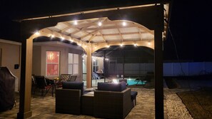 Eine überdachte Terrasse im Freien mit Sitzgelegenheiten und einem Poolbereich.