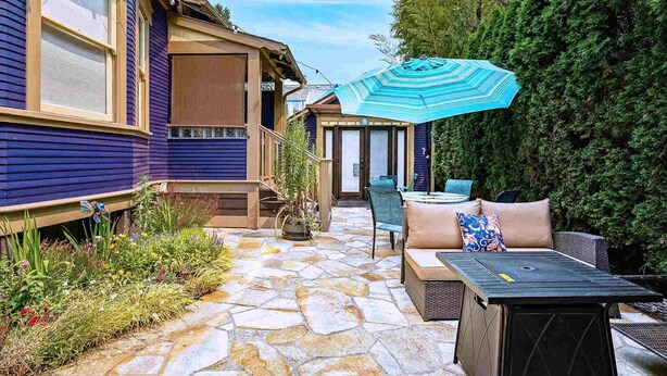 A patio with stone flooring, outdoor furniture, and a large umbrella. - Patio Villa: sleeps 1–4; 2 kitchens; gas fire pit (Portland)
