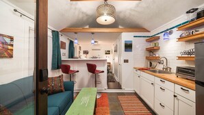 A compact kitchen with white cabinets, a wooden countertop, and a hanging light fixture. - Patio Villa: sleeps 1–4; 2 kitchens; gas fire pit (Portland)