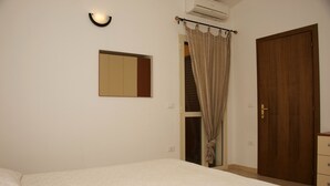 A bedroom with a bed, a wardrobe, a mirror, and a curtain. - Tommy House - Convenient, functional and comfortable home (Orosei)
